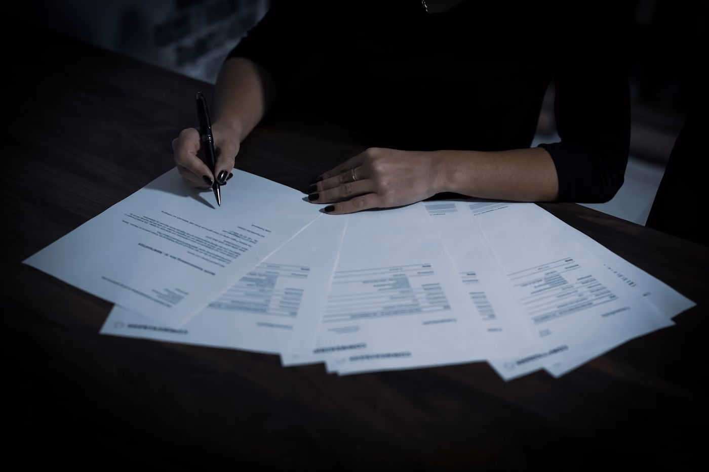 Persona signant documents sobre una taula